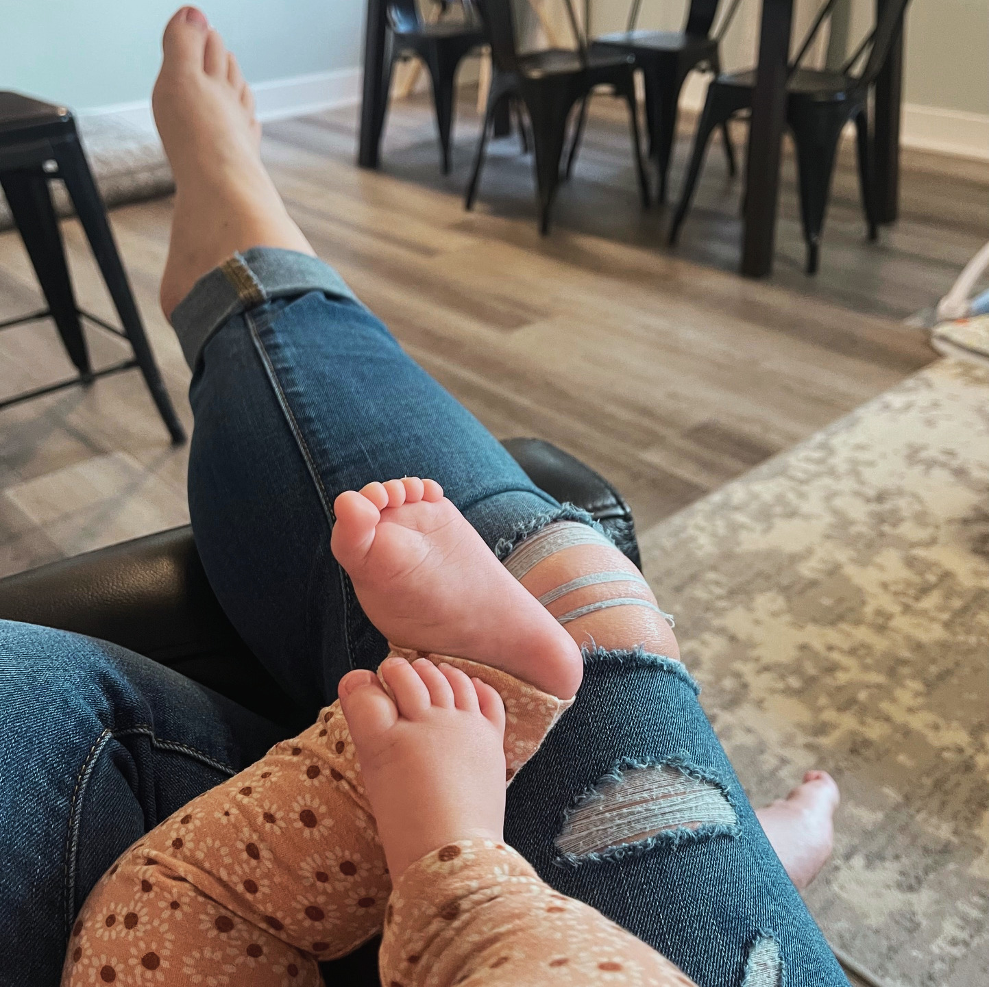 View of legs and feet with daughter sitting in mother's lap