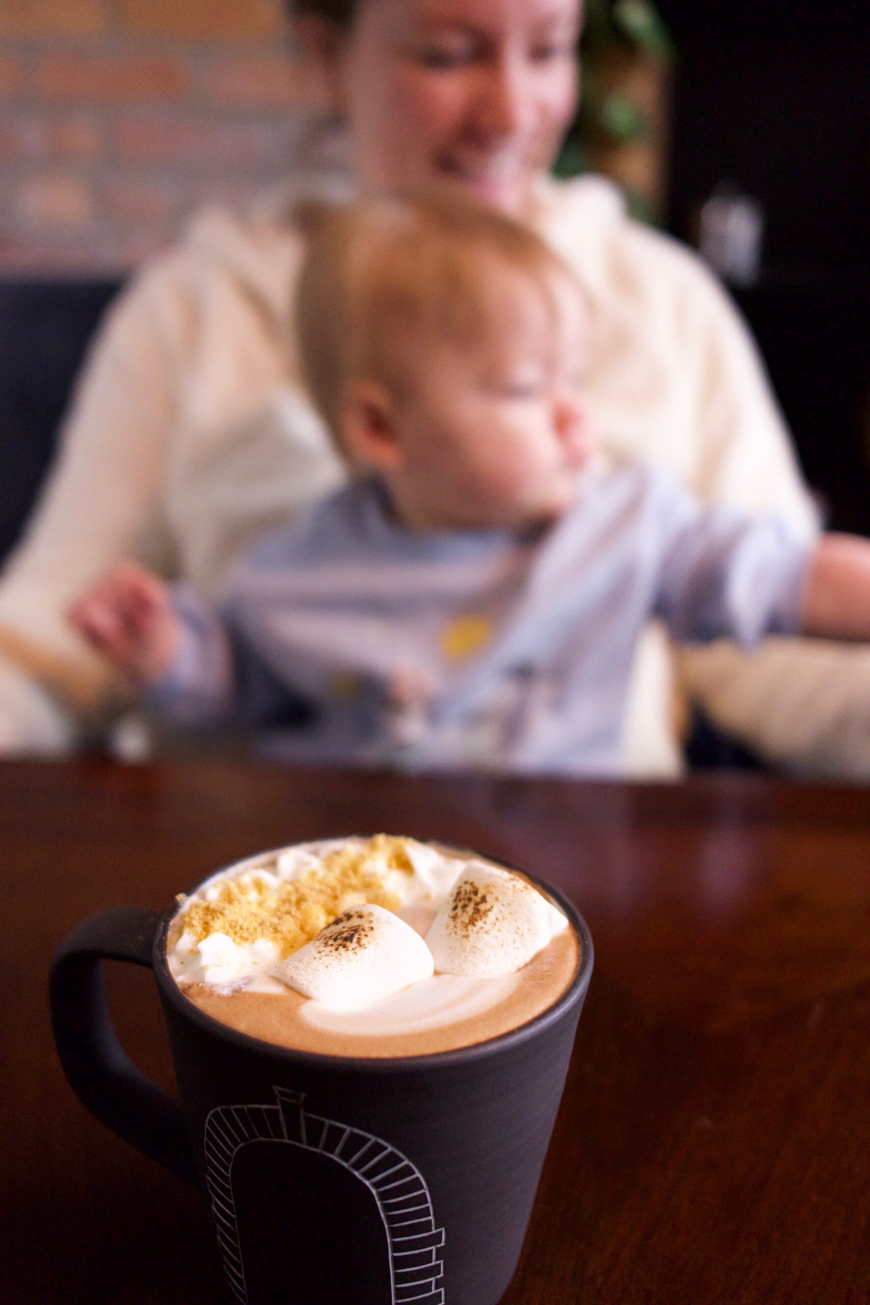 Kait and daughter unfocused in the background with a smore's coffee in focus
