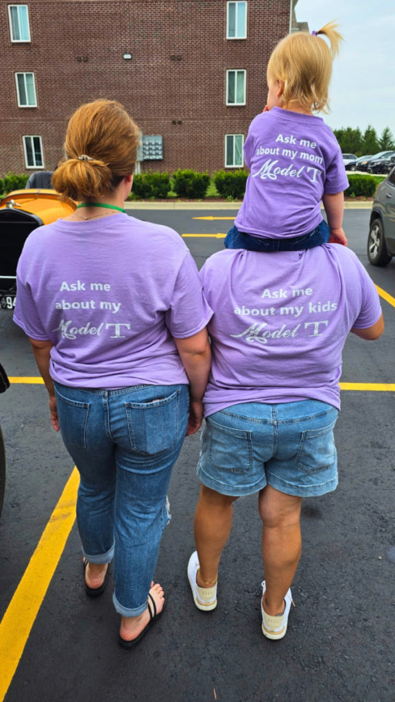 Kait, her mom, and her daughter wearing shirts that say "ask me about my Model T," "ask me about my kid's Model T," and "ask me about my mom's Model T."